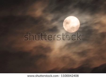 Motion picture of a rain cloud drifting through the moon at night.