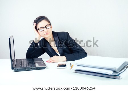 attractive sleepy brunette woman (business lady) in stylish business suit and glasses with fake eyes painted on paper sleeps in the workplace with laptop and a bunch of folders in office deadline