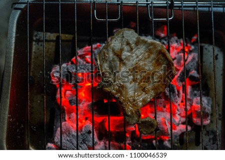 closeup of grilled steaks on barbecue with burning embers 2