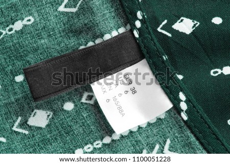 6 size textile clothes label on green cotton background closeup