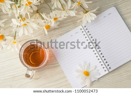 Hot tea cup on the table and notebook with flowers for Good morning or relaxing moments . copy space for text or Use of photo card background and Insert into message .