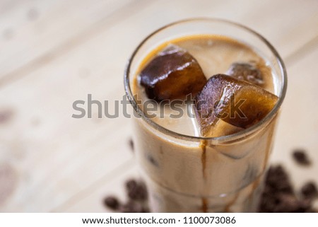 Espresso coffee frozen into ice cube mixed with milk on wooden background