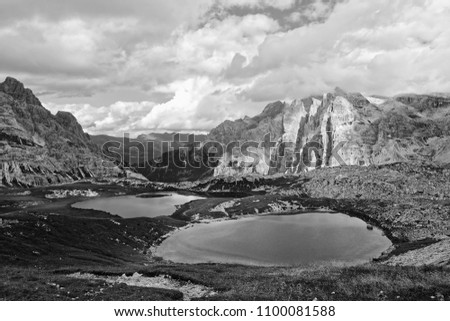 Mountains of the famous Sesto Dolomites with clouds and fog around and a lake, black and white photo, Alps, south tyrol, Italy, Europe