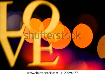 Lights of colorful garland defocused as beautiful background. Holiday concept. Christmas holiday decoration with word love. Lights of christmas garland blurred on black background