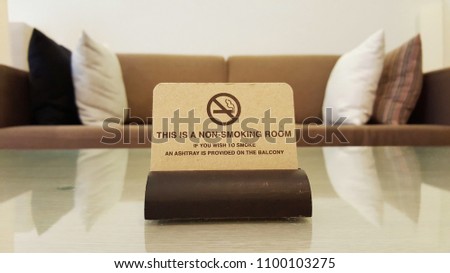 blurry non smoking room sign on glass table and pillows on the sofa.