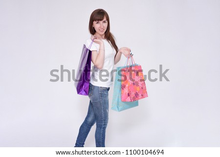 I love shopping. Portrait of a beautiful brunette girl on a white background with packages from a store. I'm standing right in front of the camera smiling and looking happy