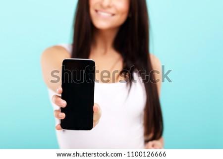 Woman using smartphone against blue wall background