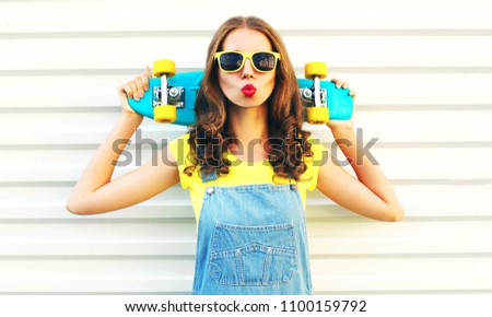 Pretty girl blowing her lips with a skateboard over a white background