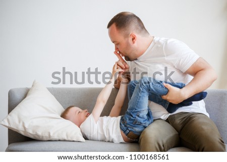 Picture of young father with son playing on sofa