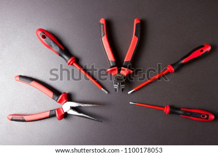 Tools for electrician with electrical insulation up to 1000 volts. Platypus, screwdriver and wire cutter on black background.