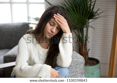 Frustrated tired young woman feeling strong headache touching forehead, depressed upset girl suffering from migraine, stressed worried teenager experiencing sudden panic attack or anxiety at home Royalty-Free Stock Photo #1100198843