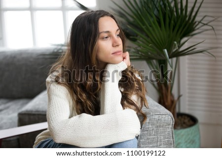 Pensive thoughtful young girl feeling lonely looking away lost in thoughts, sad depressed teenager spending time alone at home in silence, melancholic meditative serious woman thinking about problems Royalty-Free Stock Photo #1100199122