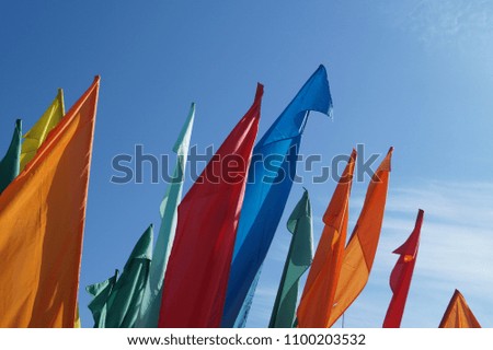 Multicolored flags against a blue sky background. Place for text.