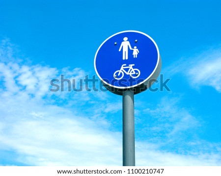 Road sign of pedestrian and bicycles area. Isolated on blue sky with clouds.