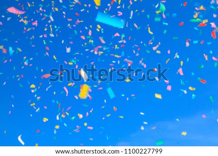 multicolored confetti on blue sky background