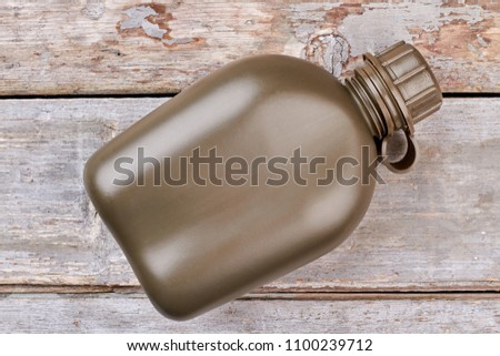 Army water bottle. Wooden desk background. Top view, flat lay.