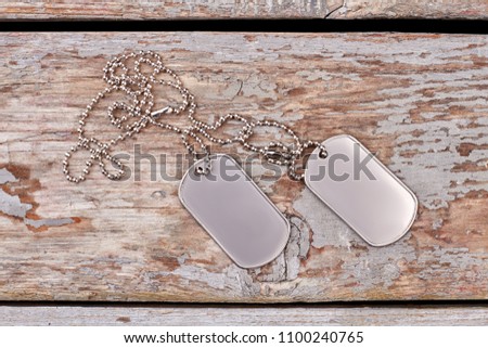 Empty silver dog tags close up. Flat lay, top view. Wooden desk background.