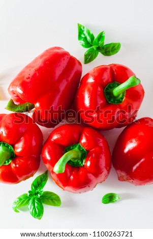 group of red ripe organic bell pepper and fresh basil leaves isolated on white