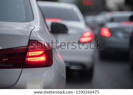 Luxury cars are on the road because of traffic jam. There are White and Silver cars with Red traffic light in thr picture.