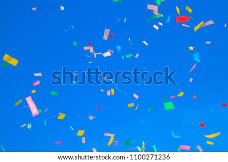 multicolored confetti on clear blue sky background