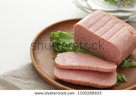 Sliced luncheon meat on wooden plate Royalty-Free Stock Photo #1100288603