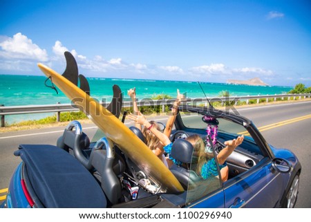 Road trip travel - girls driving car in freedom. Happy young girls cheering in convertible car on summer Hawaii vacations.