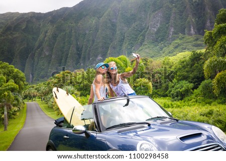 car road trip vacation young people taking selfie photo with phone during summer travel vacation. Tourists couple taking photos on Hawaii in convertible car, with smartphone camera