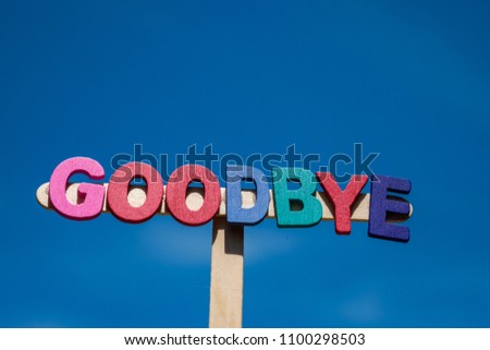 Multicolored word Goodbye from wooden alphabets over sky and clouds as background