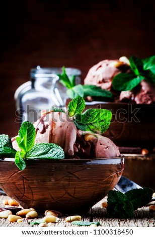 Chocolate ice cream with nuts in bowls on old wooden background, selective focus