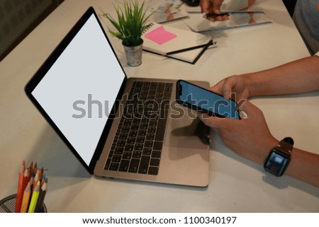Cropped shot of an unrecognizable businessman using a smart phone and smart watch at desk in office. mobile phone blank screen for graphic montage.