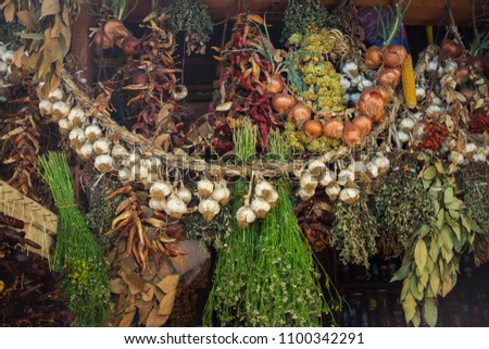 Dry garlic, red chilly pepper, herbs, spices and greens hanging under roof on local food market in asian, middle east or caucasian country.
