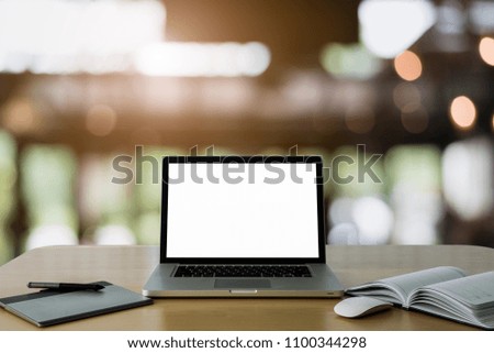 Workspace wooden desk on Laptop with blank screen and wireless mouse and graphics tablet and notebook,at cafe blurred background of light bokeh.
