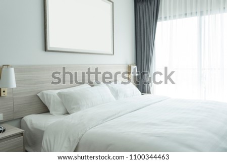 white bedding and pillow in hotel room, pillows on the bed with picture frame on wall.