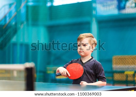 little child plays table tennis in the gym