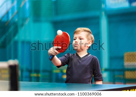 boy in gray t-shirt playing table tennis, the moment of impact on the ball