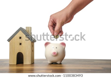 Investor hand hold a coin with save in the piggy bank put on the money on home model for family background,Saving money