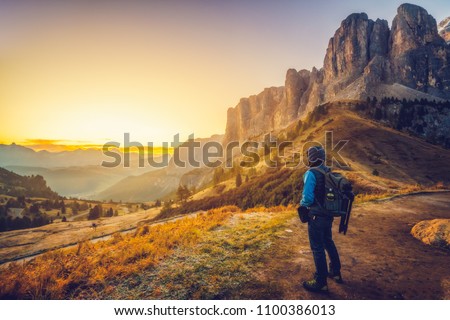 Man traveler traveling alone in breathtaking landscape of Dolomites Mounatains at sunrise in summer in Italy. Travel Lifestyle wanderlust adventure concept. Wanderer in wilderness. Royalty-Free Stock Photo #1100386013