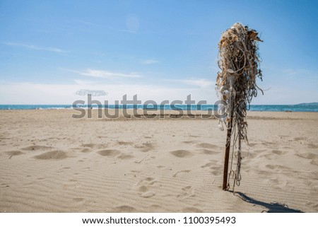 Very picturesque and minimalist view of the beach, beach, sea, skyline, the sky is blue, and in the foreground there is a column with nets and floats for fishing