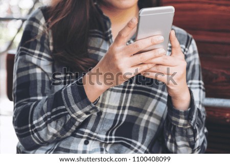 Closeup image of a woman holding , using and looking at smart phone 