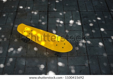 Yellow penny board stands on a gray tile