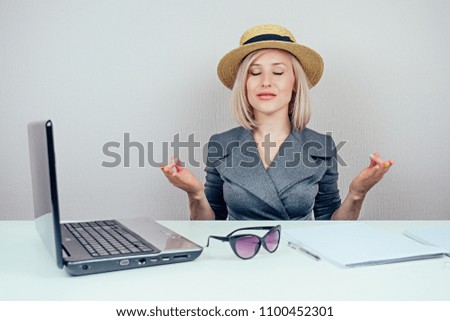 attractive smart multitasking female person (business lady) in stylish business suit and a straw hat meditatesin and dreams about vacation in office . travel concept and dismissal