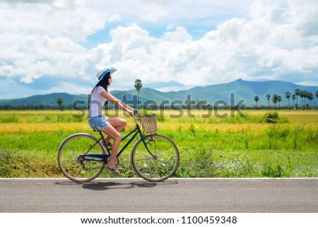 woman traveler enjoying for  view of rice field. Asian lady tourist riding a bicycle and looking for view of nature on holiday.