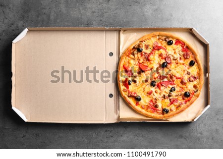 Cardboard box with delicious pizza on table, top view