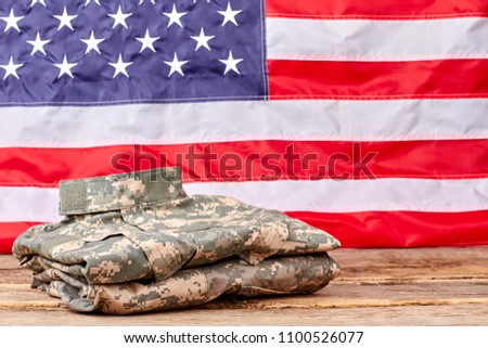 Neatly folded camouflage clothes of us army soldier. Huge american flag background.