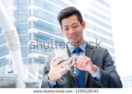Young handsome Asian businessman using smartphone outdoors touching on screen with virtual digital interface showing application icons