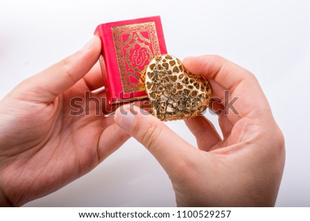 Hand holding Heart shape  and Islamic Holy Book Quran