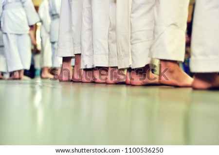 Children in Kimano stand barefoot on the wooden floor in the gym.