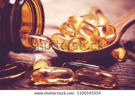 Close up vitamin D and Omega 3 fish oil capsules supplement on wooden plate for good brain , heart and health eating benefit Royalty-Free Stock Photo #1100543354