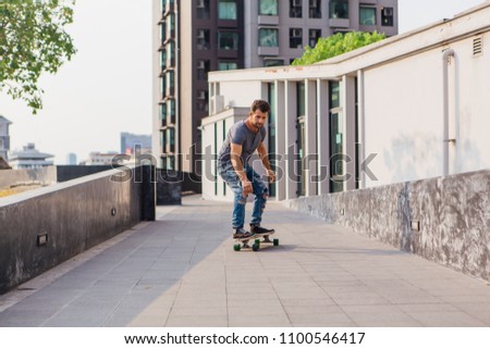 Young handsom man with beard riding a longboard on the street.