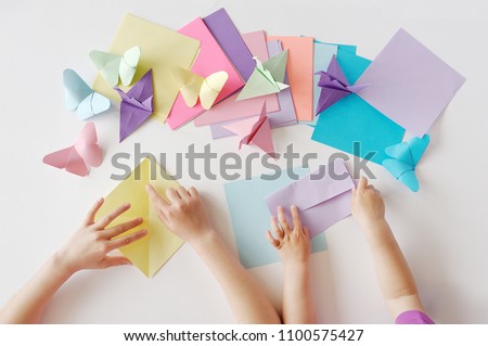 Children's hands do origami from colored paper on white background. lesson of origami Royalty-Free Stock Photo #1100575427
